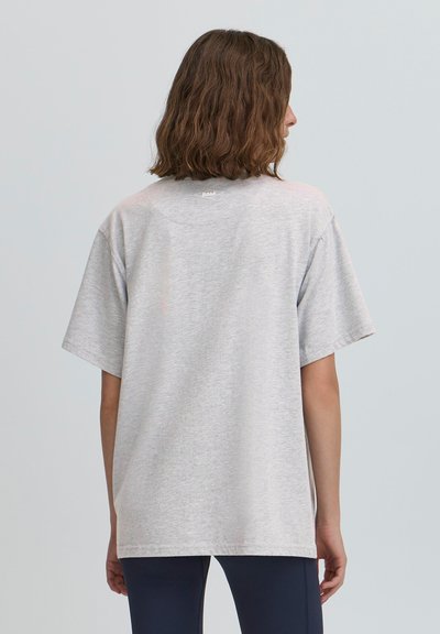 Pelēks īsām piedurknēm T-krekls ar brīvu piegriezumu, mīksta tekstūra un neliels logs aizmugurējā kakla daļā. Materiāls izskatās viegls un ikdienišķs.