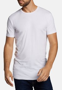 Witte T-shirt met korte mouwen van gladde stof, met een ronde hals en een slim fit ontwerp, gedragen met donkerblauwe jeans.