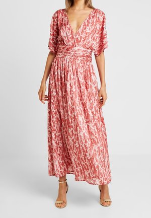 Robe longue à motif floral rouge et blanc avec un décolleté en V profond, des manches courtes et une taille froncée. Tissu doux qui tombe fluidement jusqu'au sol.