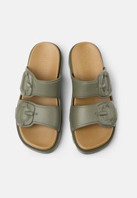 Green rubber slide sandals with two adjustable buckle straps, featuring a tan cushioned footbed and textured sole.