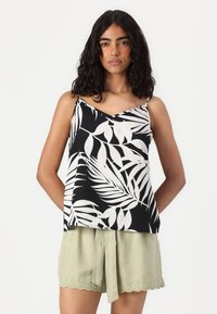 Débardeur noir avec un motif de feuilles blanches, doté de fines bretelles et d'un col en V. Associé à un short vert clair avec une taille nouée et un ourlet festonné.