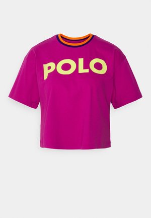 T-shirt à manches courtes et court en magenta vibrant avec un imprimé jaune "POLO" et un col ras-du-cou rayé orange et violet. Tissu en coton doux.