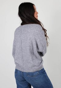 Pull léger gris clair avec une coupe décontractée, des manches larges et une couture centrale dans le dos. Fabriqué à partir d'un tissu doux avec une texture lisse.