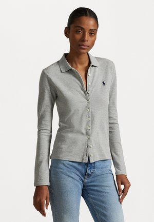 Grau langärmliges Poloshirt mit Kragen, ausgestattet mit Knopfverschluss und dunkelblauem Logo-Patch. Getragen mit hellblauen Jeans.