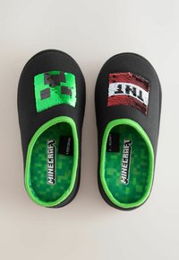 Black fabric slippers featuring a green pixelated Creeper face and a red sequined accent. The interior has a green pixelated lining.