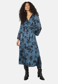 Abito lungo e fluido di colore blu con motivo floreale nero e sottili righe verticali. Presenta un design avvolgente e maniche lunghe. Texture del tessuto accessibile.