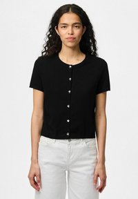 Musta lyhythihainen neuletakki, joka on valmistettu neulemateriaalista, pyöreä pääntie ja edessä sydämenmuotoiset hopeanväriset napit.