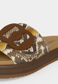 Σανδάλι τύπου slide με καφέ ψεύτικη ξύλινη σόλα, λουράκι με σχέδιο φίδι και μεγάλο καφέ αγκράφα σε ανοιχτό φόντο.