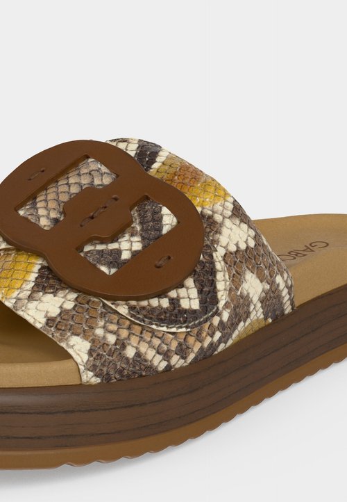 Sandale à enfiler avec semelle aspect bois marron, bride imprimé serpent avec une grande boucle marron sur fond clair.