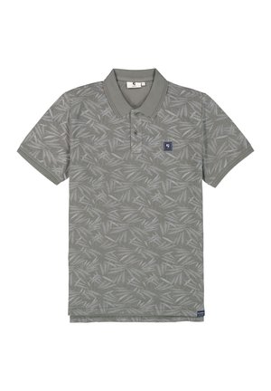 Polo en verde suave con un patrón de hojas. Cuenta con un cuello, tres botones y un pequeño parche con el logo en el lado izquierdo del pecho. Mangas cortas.