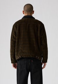 Brown corduroy jacket with a black sherpa collar, featuring a straight cut, visible stitching, and snap buttons at the hem and pockets.