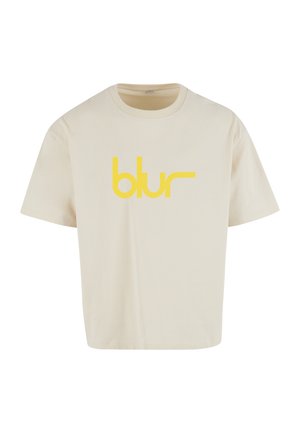 Bézs színű pamut póló kerek nyakrésszel és rövid ujjakkal. A mellkasnál egy feltűnő, sárga "blur" logó található.