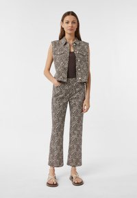 Brązowa kamizelka dżinsowa bez rękawów w panterkę i dopasowane rozkloszowane spodnie. Strój ma delikatną teksturę i detale w postaci przednich kieszeni.