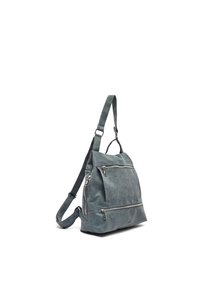 Blå läderryggsäck med justerbar rem, två framfickor med dragkedja och en texturerad yta. Kompakt triangulär form, minimal hårdvara.