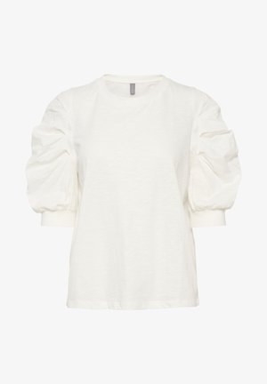 Camiseta blanca con mangas abullonadas y escote redondo. Confeccionada en un material ligero con una textura suave. El dobladillo es ligeramente más largo en la parte posterior.