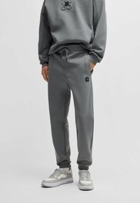 Grijze joggers van zacht materiaal, met een elastische tailleband met aantrekkoord en een klein logo-opdruk op de zak.