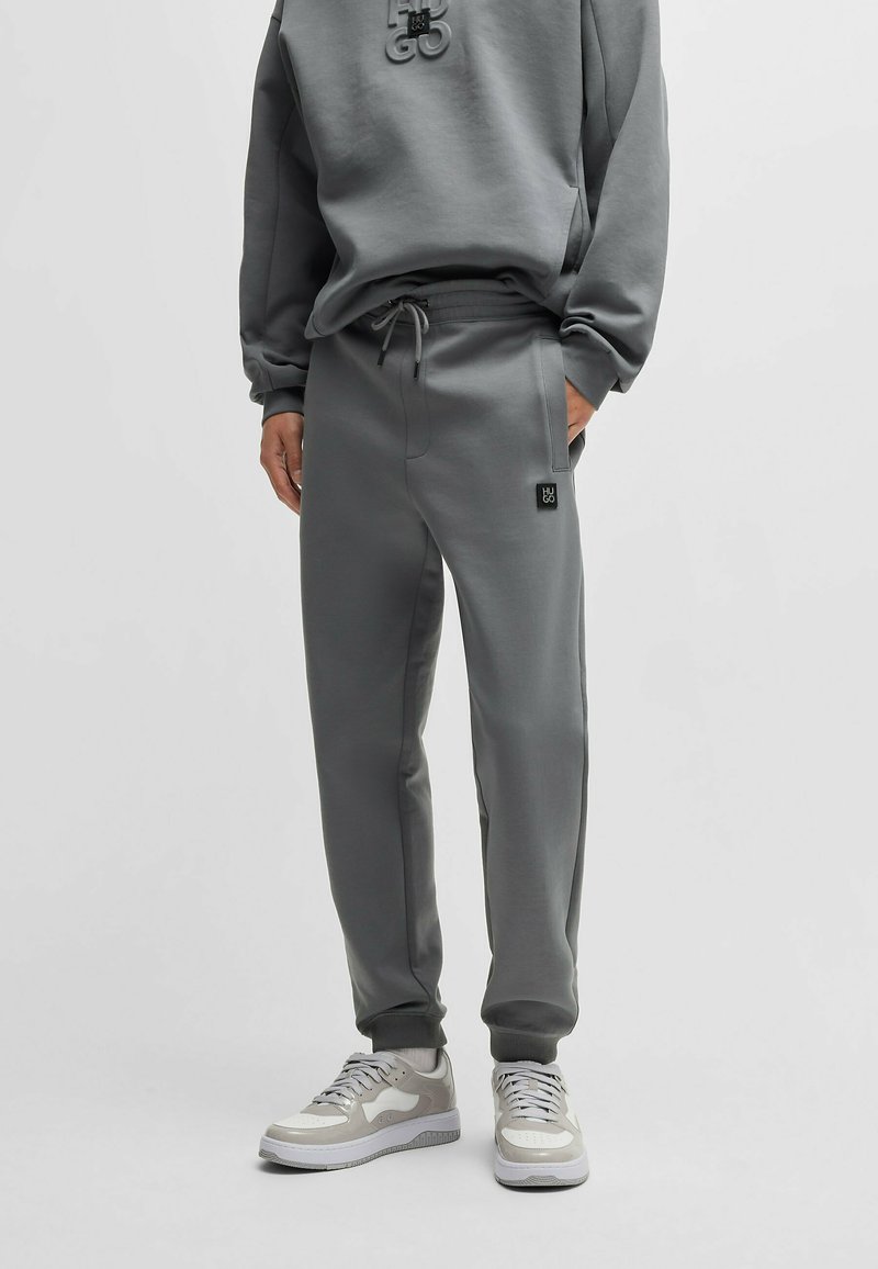 Grijze joggers van zacht materiaal, met een elastische tailleband met aantrekkoord en een klein logo-opdruk op de zak.
