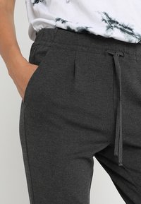 Gray jogger pants made of soft fabric with an elastic waistband, drawstring closure, and side pockets. Features a smooth texture.