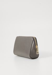 Pouch cosmetic din piele gri, cu o suprafață texturată, formă triangulară și fermoar din aur. Design compact, potrivit pentru călătorii.