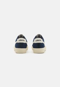 Levi's sötétkék sportcipő krém színű részletekkel és texturált talppal. Jellemzője a logó a saroknál és egy sima, tartós anyagú felsőrész.