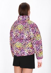 Fényes leopárd mintás pufi dzseki élénk rózsaszín, sárga és fekete árnyalatokkal. Magas gallérral és elasztikus mandzsettákkal rendelkezik.