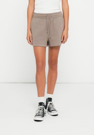 Brune bomullsblanding shorts med elastisk livrem og snor. Kombinert med svarte høye sneakers og hvite ankelstrømper.