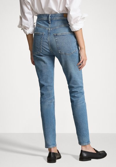 Light blue denim jeans with a high waist, tapered legs, and two back pockets. The fabric has a subtle texture and distressed detailing.