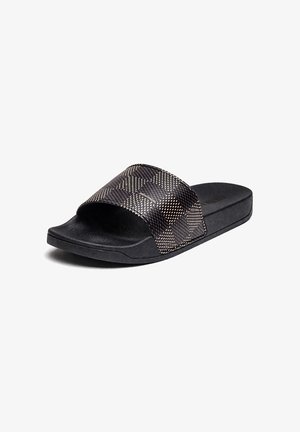 Sandalia tipo slide negra con suela texturizada y amplia correa a cuadros con pequeño patrón de puntos en beige y marrón oscuro.