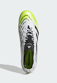 White and black soccer shoe with a textured upper, neon green accents, and a lace-up design, featuring a lightweight construction and padded insole.