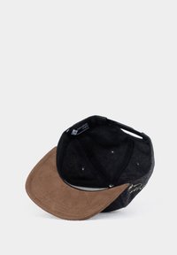 Dunkelgraue Kappe mit einem braunen Wildledervisier. Das Innere ist mit schwarzem Stoff ausgekleidet, verfügt über Belüftungsöffnungen und ein Logoetikett auf der Innenseite.