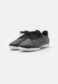 Scarpe sportive nere con una superficie strutturata, cuciture a contrasto e suola bianca. Caratteristiche includono chiusura con lacci e design perforato.