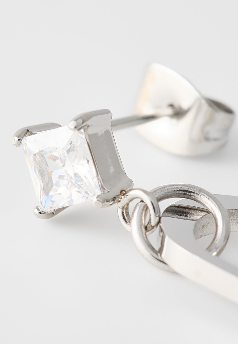 Boucles d'oreilles en argent ornées d'une pierre précieuse claire, carrée et facettée, sertie dans un support à griffes, fixées à un anneau circulaire et à une tige de soutien.
