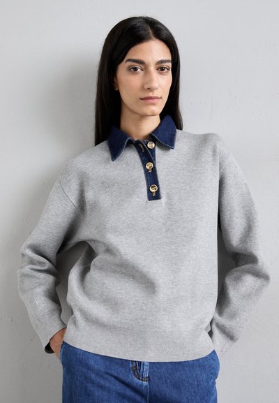 Sweatshirt grigio con colletto in denim e bottoni dorati, caratterizzato da una vestibilità relaxed e polsini a coste. Design semplice con dettagli blu.