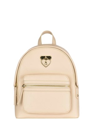 Piccolo zainetto beige con tasca frontale con zip e un charm dorato a forma di cuore sul pannello anteriore superiore.