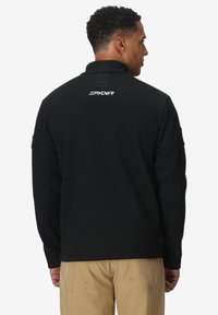 Pullover in pile nero con superficie testurizzata, colletto alto e logo sul retro. Presenta maniche lunghe e una vestibilità comoda.