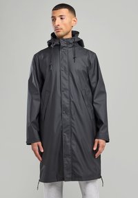 Black waterproof raincoat with a hood, snap buttons, front pockets, and adjustable drawstrings. Smooth, shiny material with a knee-length cut.