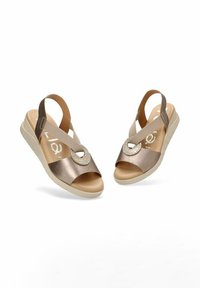 Sandalias de tacón bajo en bronce con una correa texturizada, acento de corte redondo y suela de un beige claro. Material suave con un ligero brillo.