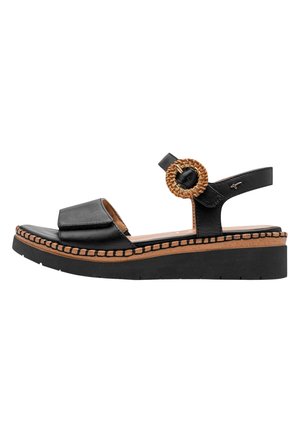 Sandalia de plataforma negra con puntera abierta, pulsera en el tobillo con hebilla redonda tejida y ribete cosido en la entresuela color marrón claro.