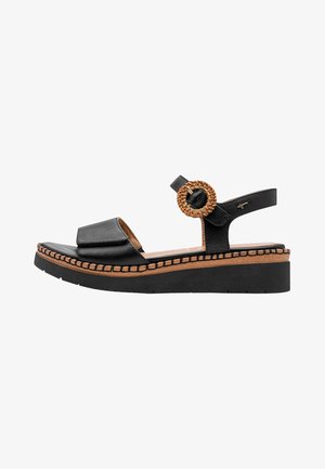 Sandalia de plataforma negra con puntera abierta, pulsera en el tobillo con hebilla redonda tejida y ribete cosido en la entresuela color marrón claro.