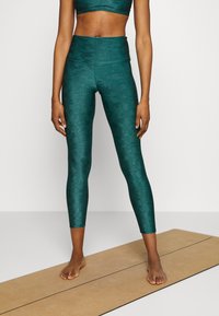 Teal färgade träningsleggings med ett texturerat kamouflage-mönster, hög midja och en jämn yta, kombinerat med en matchande sportbh.