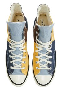 Höga kanvas sneakers med blå, gul, brun och marin paneler, vita snörningar och gummikappa vid tån med svart kant.