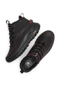 Bottes de randonnée imperméables noires avec des accents rouges, tige texturée, semelle en caoutchouc avec des crampons profonds, et lacets réfléchissants pour une meilleure visibilité.