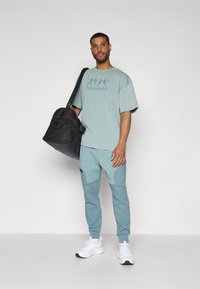 Under Armour ATHLETES  - Apdrukāts T-krekls - serpentine/jasper blue