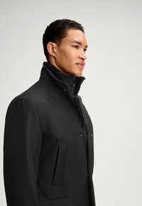 Schwarze isolierte Jacke mit hohem Kragen, Frontreißverschluss und zwei Seitentaschen. Verfügt über eine glatte Textur und ein Fleece-Futter für zusätzliche Wärme.