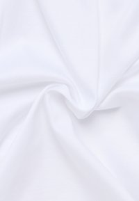 Weißer Stoff mit einer glatten, leicht matten Textur, der sanfte Falten und Drapierungen zeigt und auf ein leichtes Material hinweist, das für verschiedene Anwendungen geeignet ist.