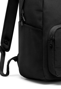 Svart ryggsäck med en strukturerad tyg, som har flera fickor med dragkedja och en sidoficka. Remmarna har ett vadderat nät för komfort.