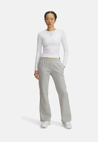 Hvid langærmet ribbet top parret med grå fleece sweatpants med snoretræk i taljen og sidelabber, båret med hvide sneakers.