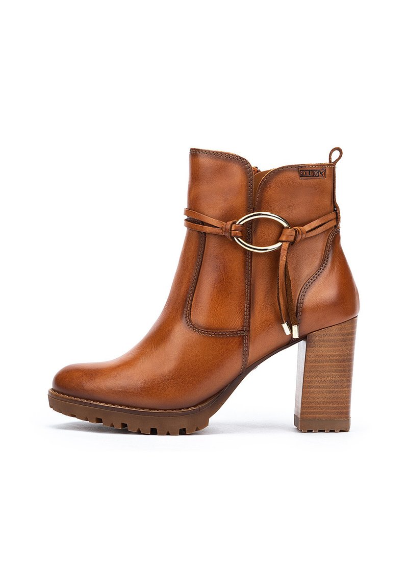 Stivale alla caviglia in pelle marrone con punta rotonda, accentuato da hardware dorato e un tacco in legno spesso. Presenta una cintura decorativa.
