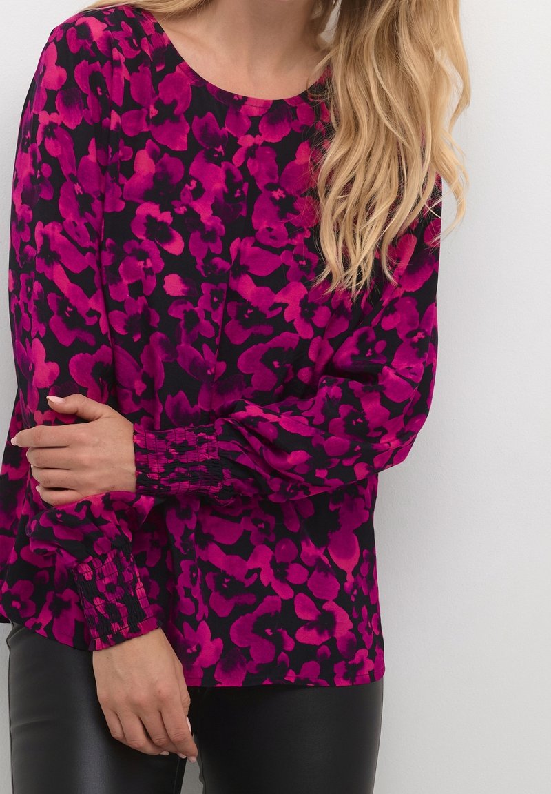 Langærmet bluse i en livlig pink og sort blomsterprint, med en rund halsudskæring og samlede manchetter, lavet af letvægtsstof.