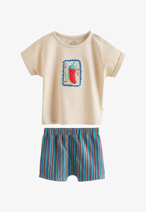 Bézs színű rövid ujjú kisgyermek póló, chilipaprika folttal, rajta az „Chillin' Out” felirat, kék, piros és barna csíkos rövidnadrággal párosítva.